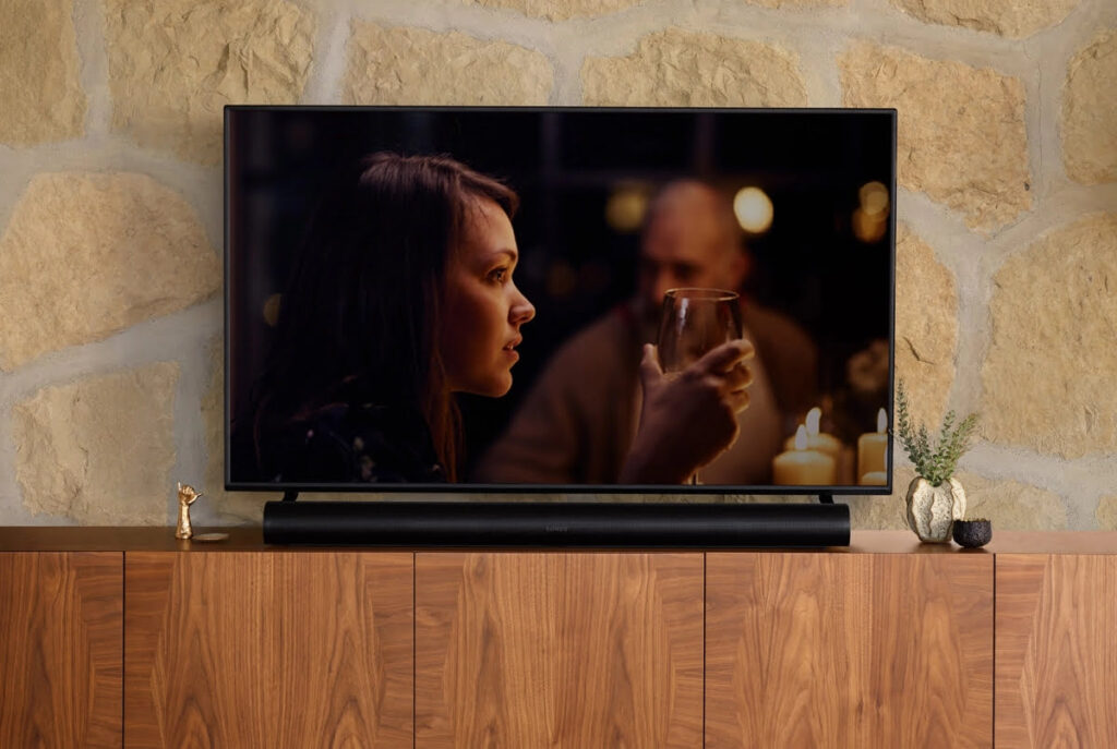 Sonos Arc gepositioneerd op een tv meubel onder een televisie.
