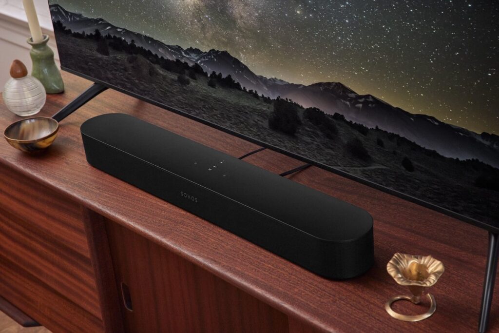 Sonos Beam zwart gepositioneerd op een tv meubel voor de televisie.